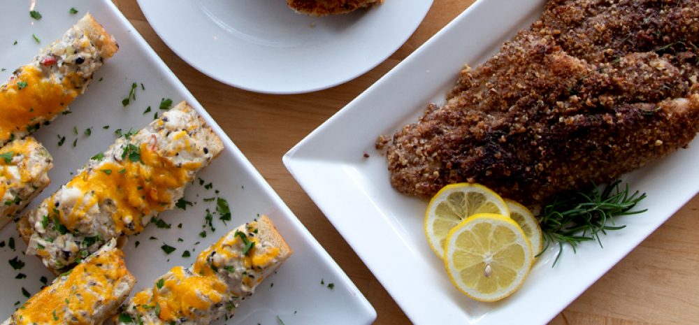 Plates of catfish cheesy bread, catfish cakes and pecan crusted catfish