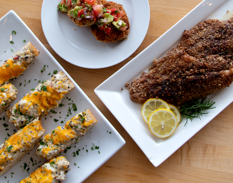 Plates of catfish cheesy bread, catfish cakes and pecan crusted catfish