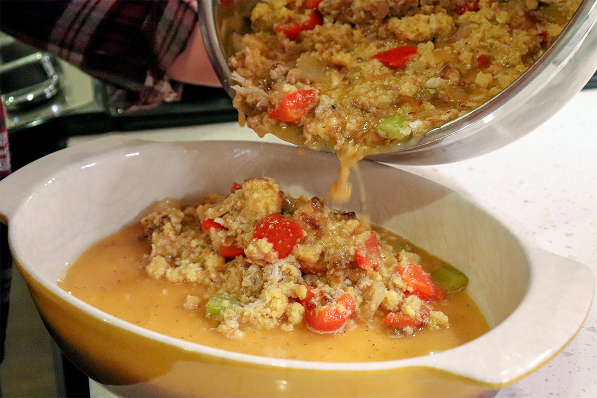 mixed cornbread dressing pouring into baking pan