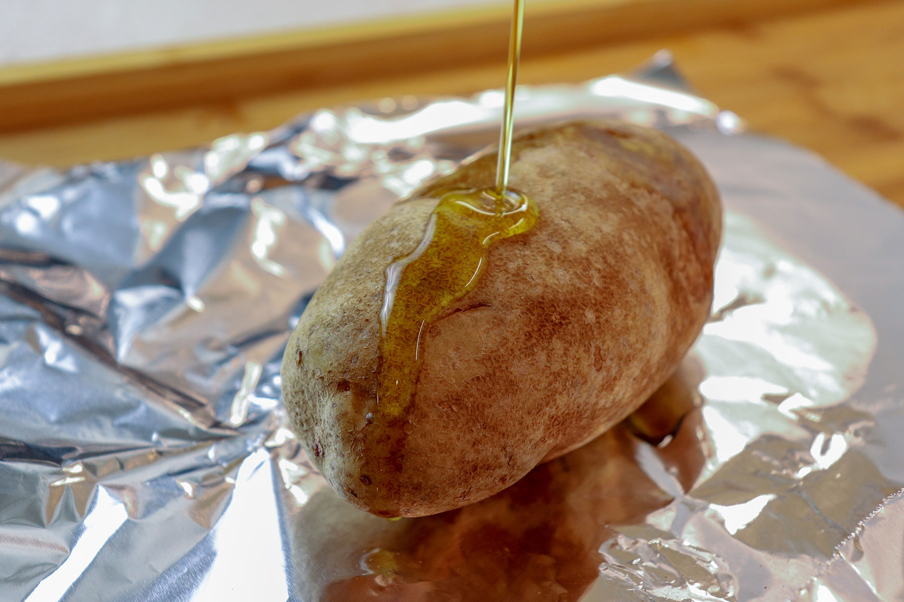 pouring olive oil onto potato