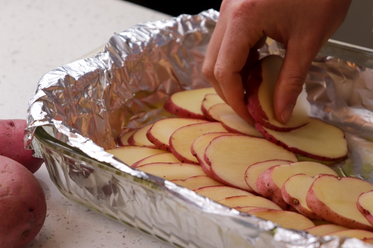 Sliced red potatoes lining baking pan