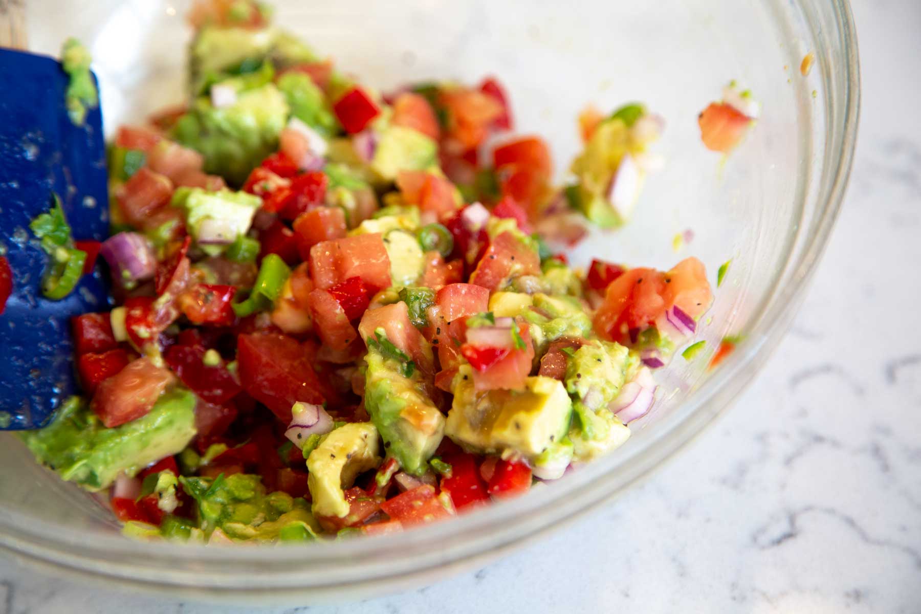 Fresh avocado, tomato, onion and other ingredients in a bowl