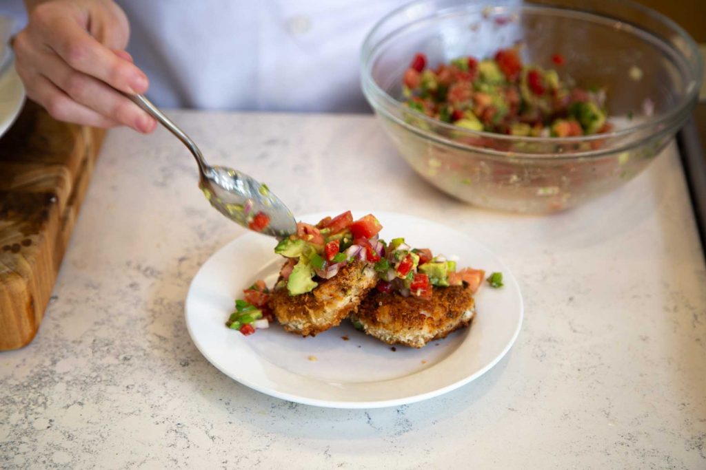 Covering Catfish Cakes with salsa