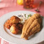 Classic Fried Catfish with hushpuppies and coleslaw on gingham table cloth