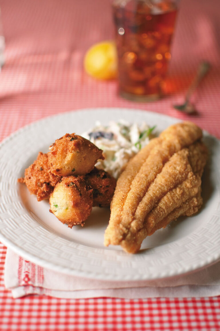 Classic Fried Catfish with hushpuppies and coleslaw on gingham table cloth