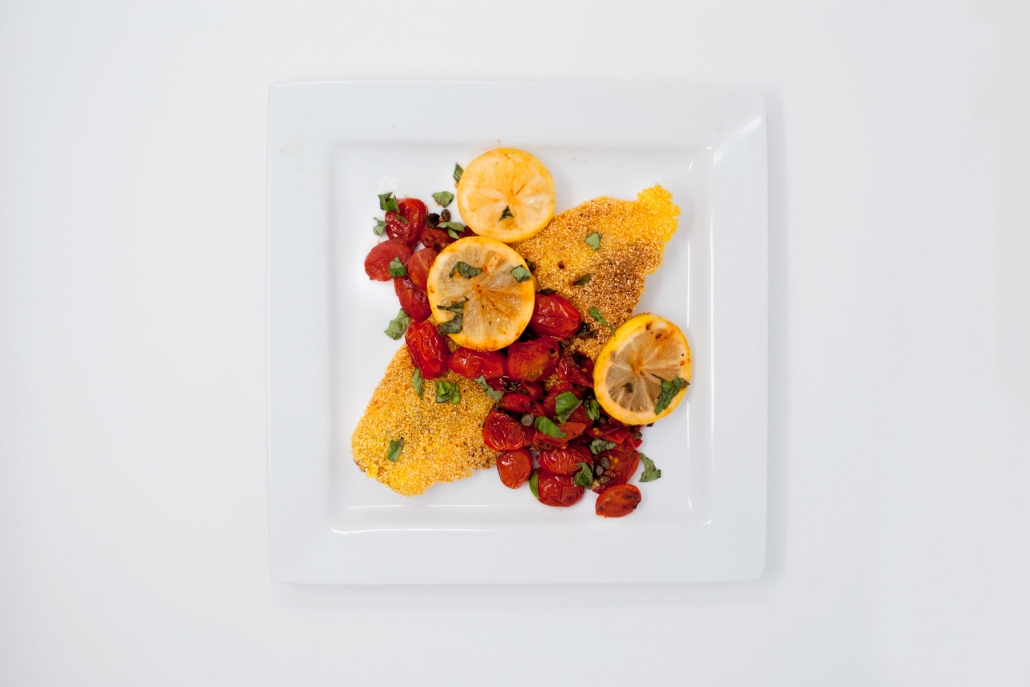 Grits Crusted Catfish topped with tomatoes on plate