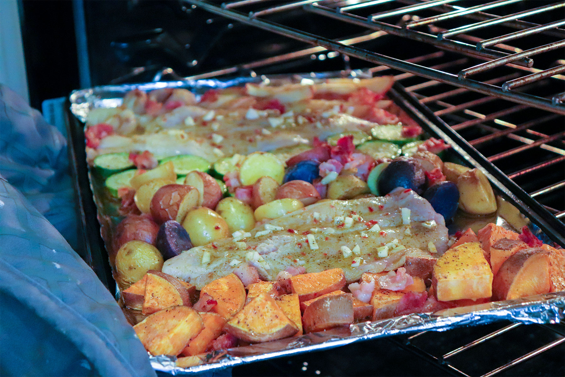 catfish added to sheet pan with veggies in oven