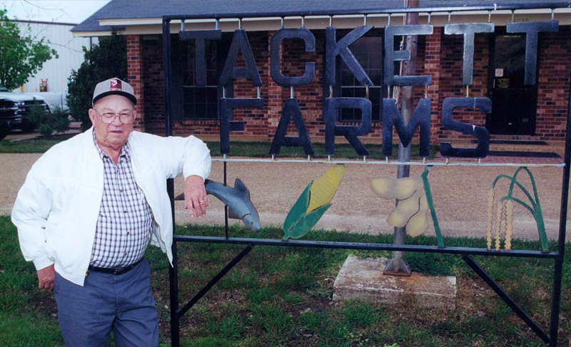 William tackett in front of Tackett Farms sign