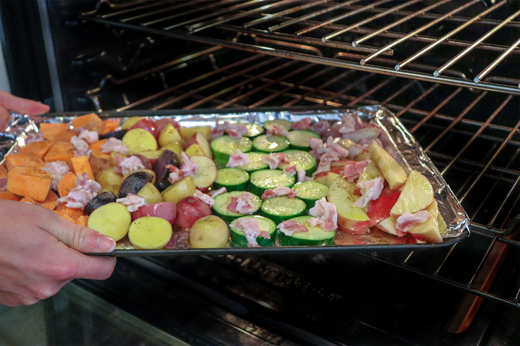 sheet pan with veggies and bacon put into oven