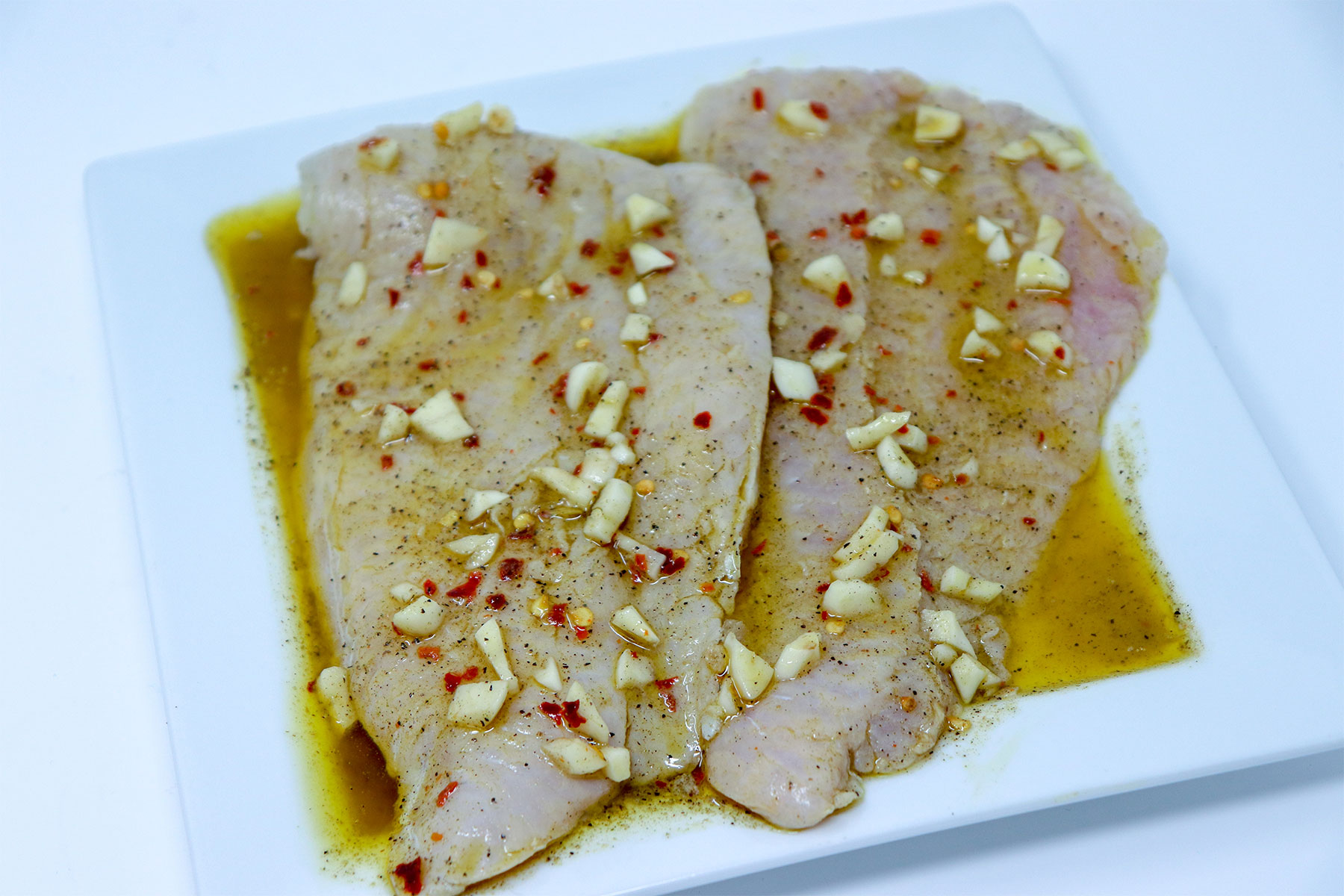 raw catfish fillets seasoned with oil, garlic and pepper