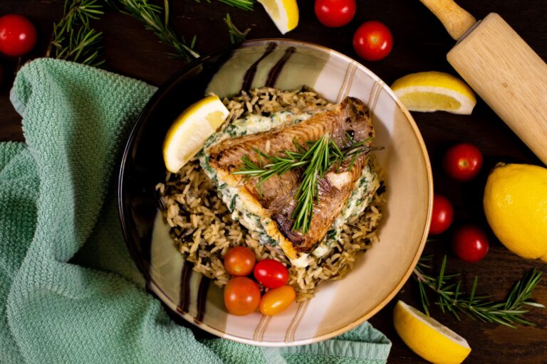 Grilled catfish fillet topped with rosemary, served over spinach and wild rice with cherry tomatoes and lemon wedges.