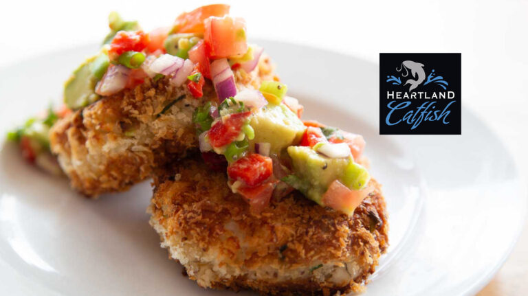 Breaded catfish cakes topped with avocado and tomato salsa, plated with the Heartland Catfish logo.