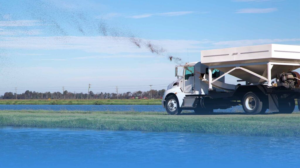 Truck driving by catfish ponds feeding the catfish.