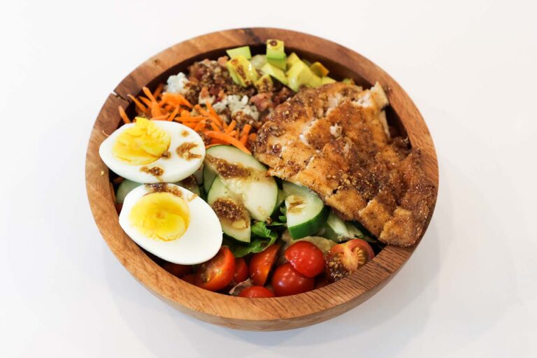 Bowl of vegetables, rice and cuts of fried catfish.
