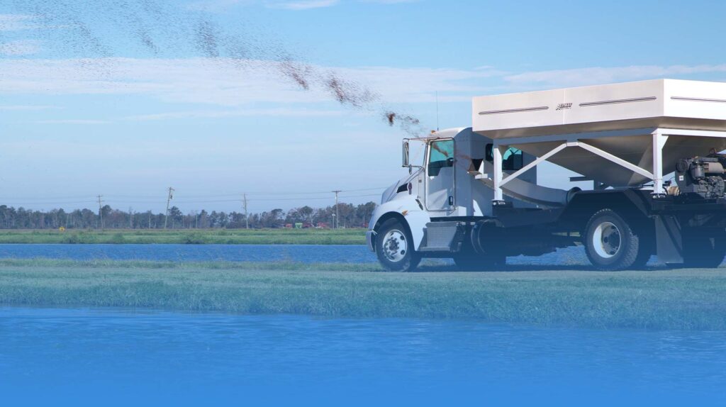 Truck driving by catfish ponds feeding the catfish.