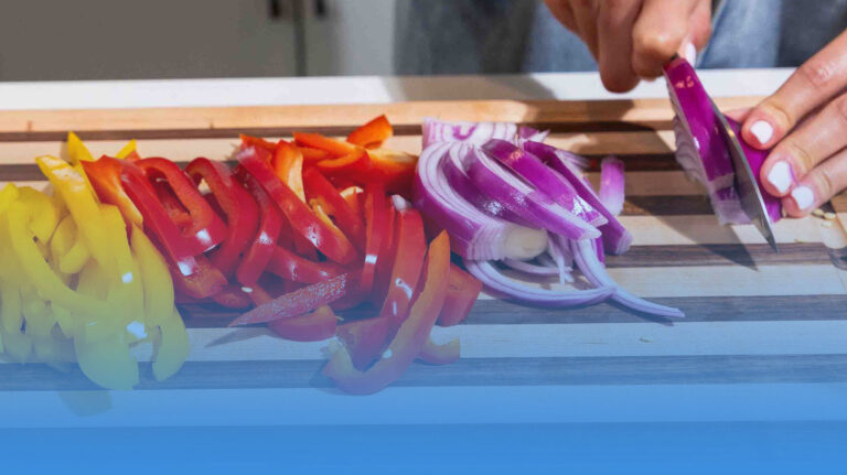 Person chopping peppers and onions.