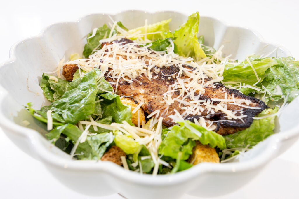 Catfish fillet sliced and served over a Caesar salad with parmesan and croutons