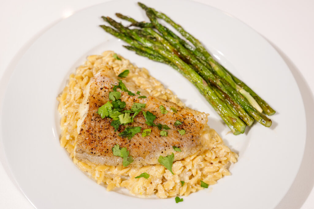 Air-fried lemon pepper catfish fillet plated with roasted asparagus and lemon orzo