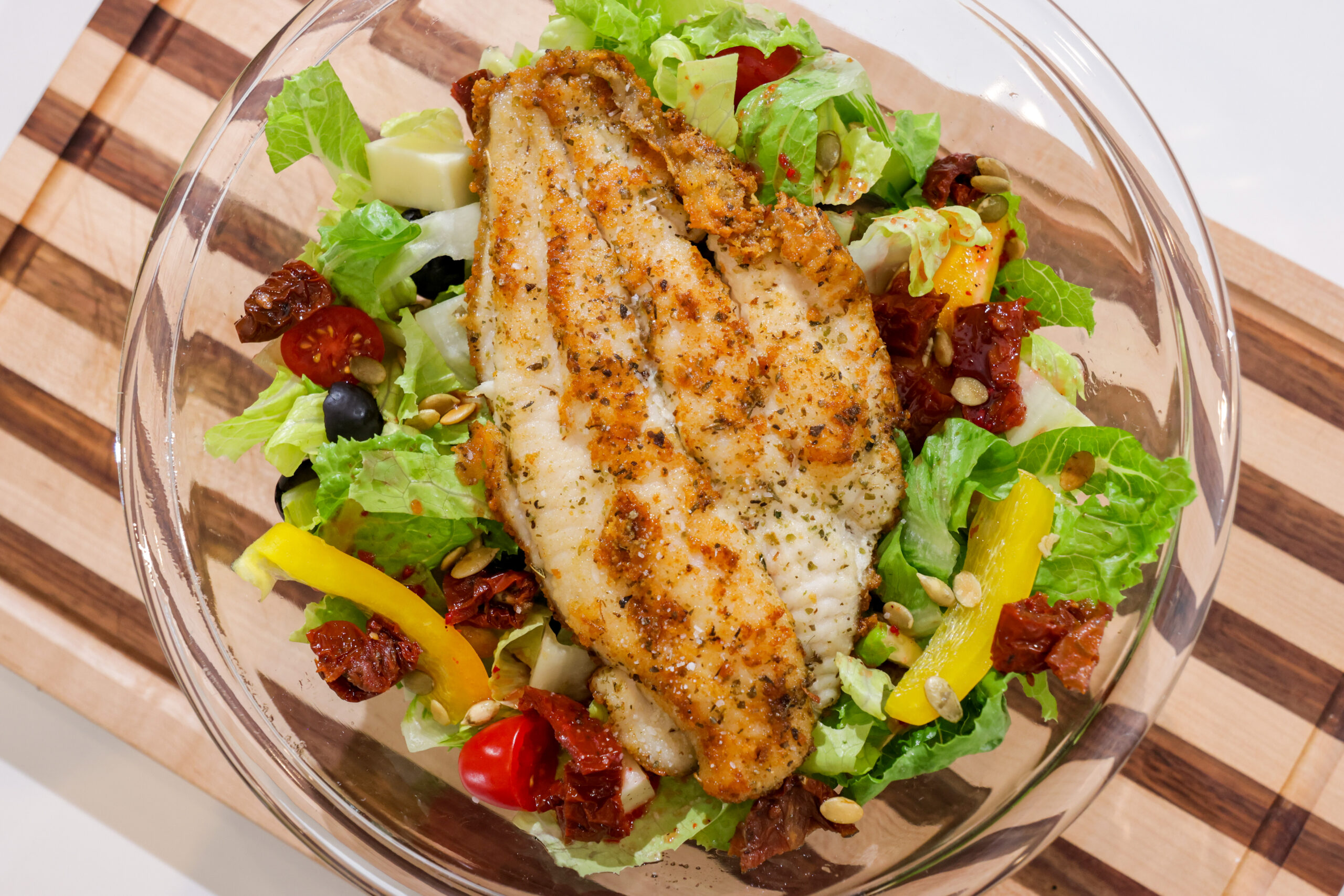 Seasoned catfish fillet served over a Tuscan-style salad with romaine, sun-dried tomatoes, olives, cherry tomatoes, yellow pepper, and pepitas.